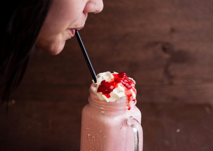 hidden gems in grande prairie county - woman drinking strawberry milkshake from mason jar