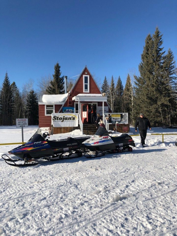 two snowmobiles with man outside storjan's - guide to snowmobiling