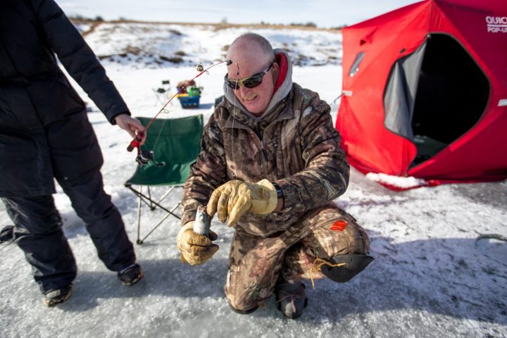 man baiting ice fishing rod