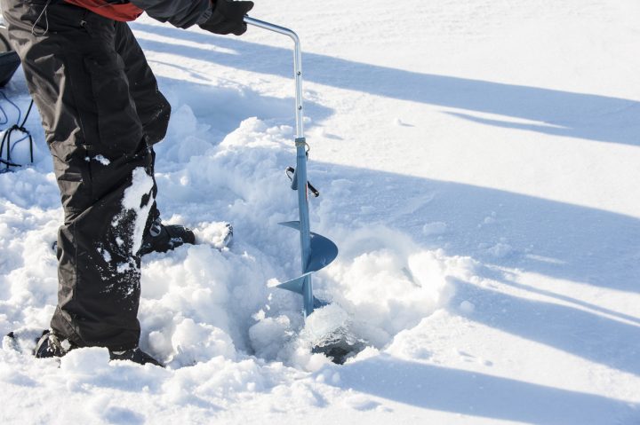 person using ice auger going ice fishing in grande prairie region