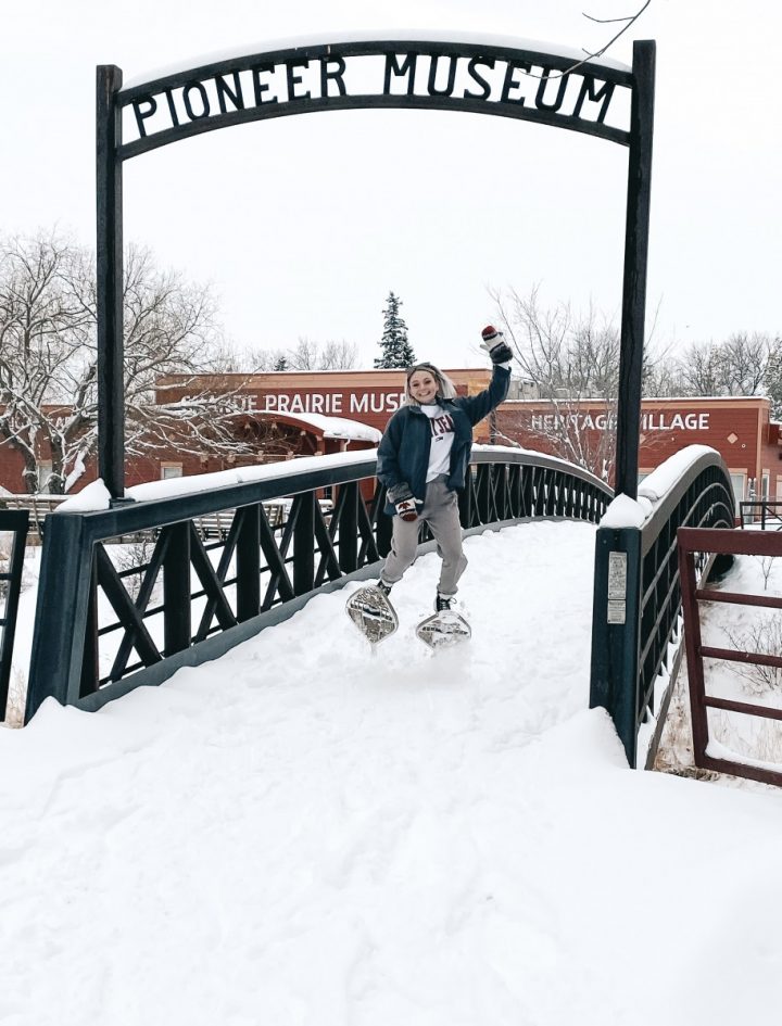 person snowshoeing in muskoseepi park by pioneer museum bridge