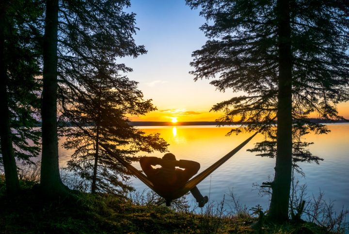 man in camping hammock watches Grande Prairie sunset